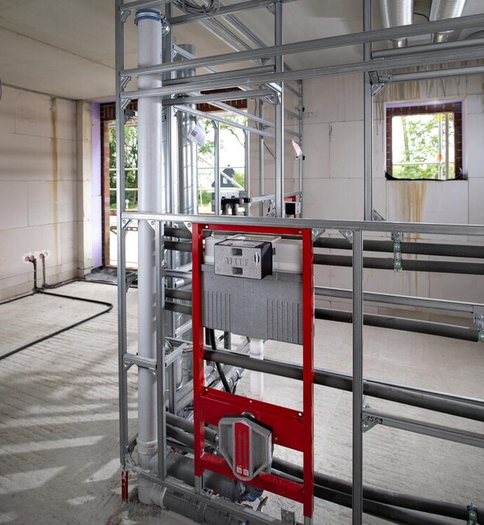 Eine industriell vorgefertigte Installationswand kommt als raumhohe Trennwand zwischen zwei Apartments zum Einsatz.
