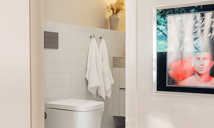 Mindre badrum med putsade väggar, avlånga kakelplattor, TECEneo duschtoalett och TECEsolid spolknapp i borstat rostfritt stål.