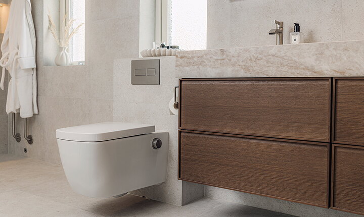 Ljust badrum med TECEneo duschtoalett, TECEsolid spolknapp, mörk träkommod och naturstenliknande ytor.